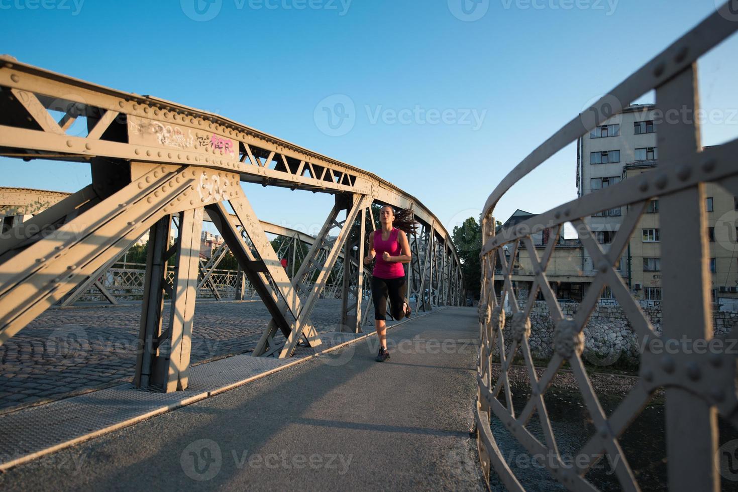woman jogging across the bridge at sunny morning photo
