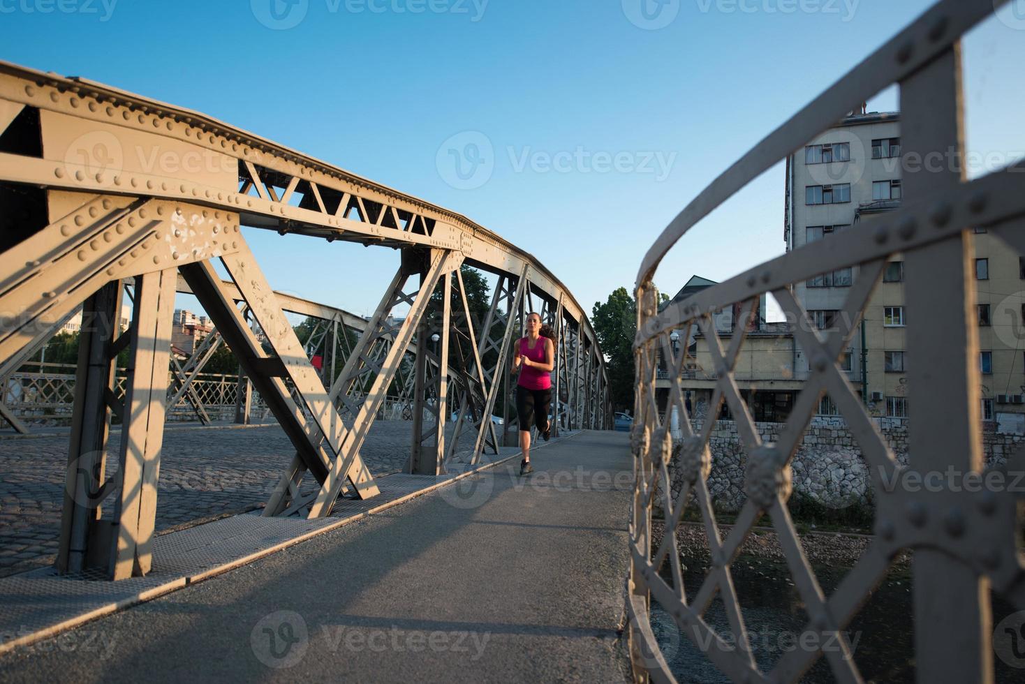woman jogging across the bridge at sunny morning photo