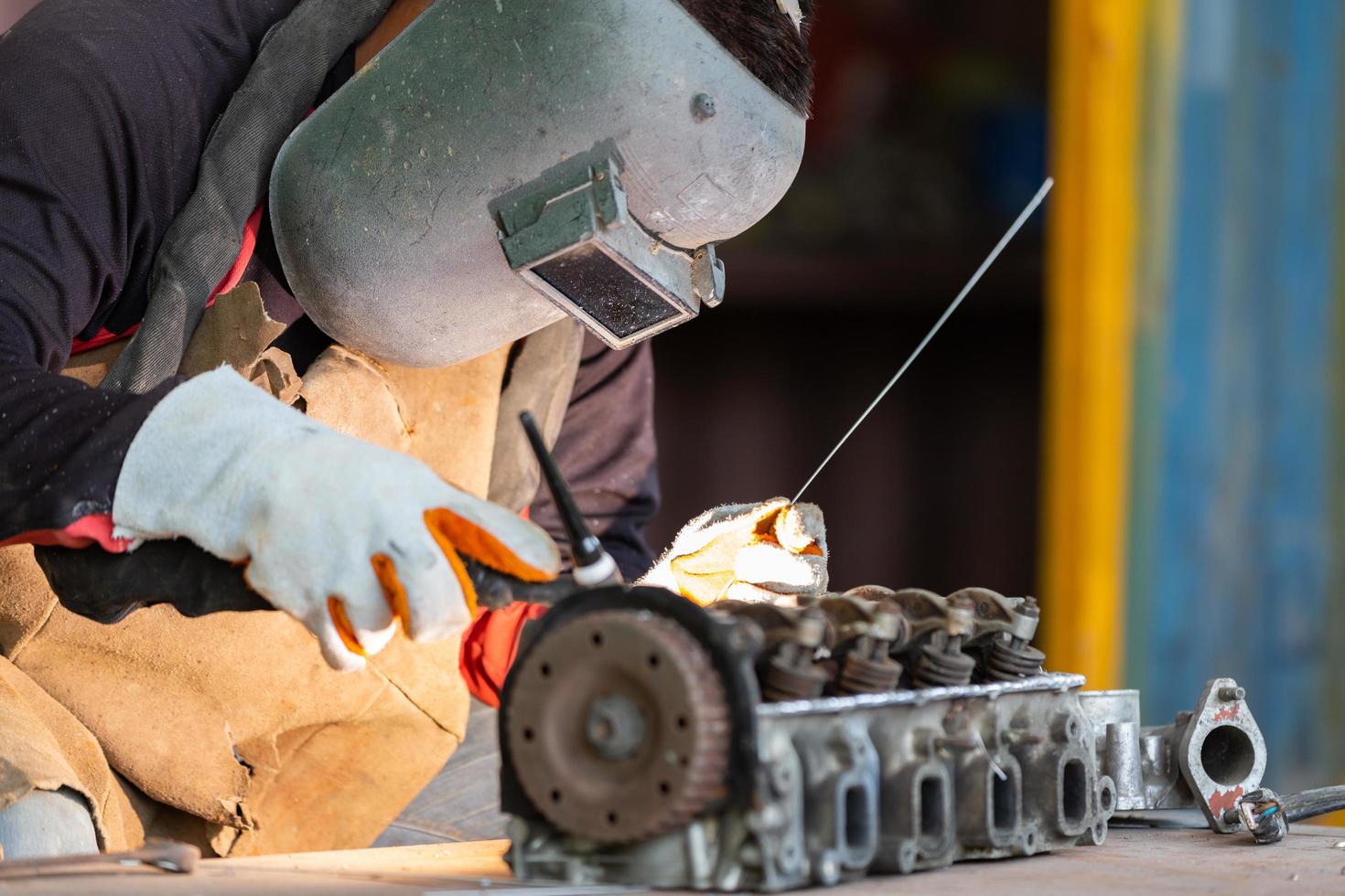 The man in the face mask is welded by argon welding. Welder industrial worker welding with argon machine. photo
