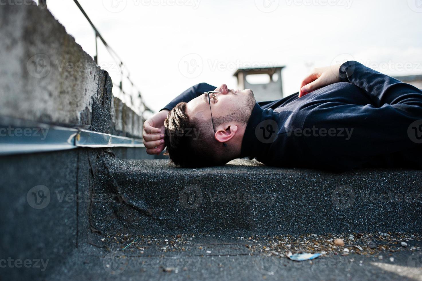 Dreamer stylish macho man in black golf and glasses posed on the roof. photo