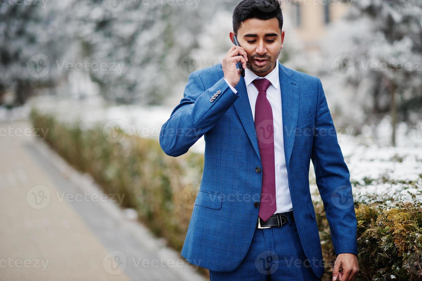 elegante modelo indio de moda en traje posado en el día de invierno y hablando por teléfono. foto