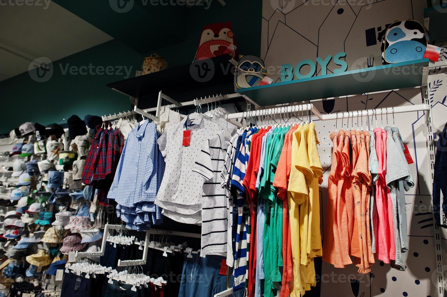 Children's bright clothes hang on the display in the baby clothing store. Boys section. photo