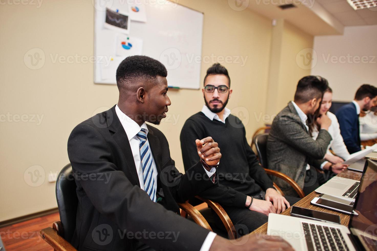 Multiracial business team addressing meeting around boardroom table. photo