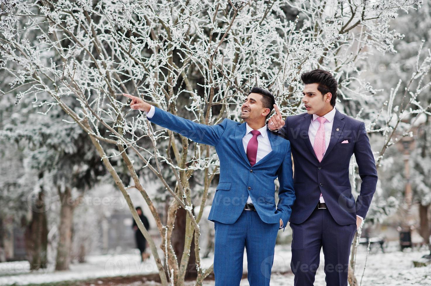 dos elegantes modelos indios de moda en traje posaron en el día de invierno, muestran algo. foto