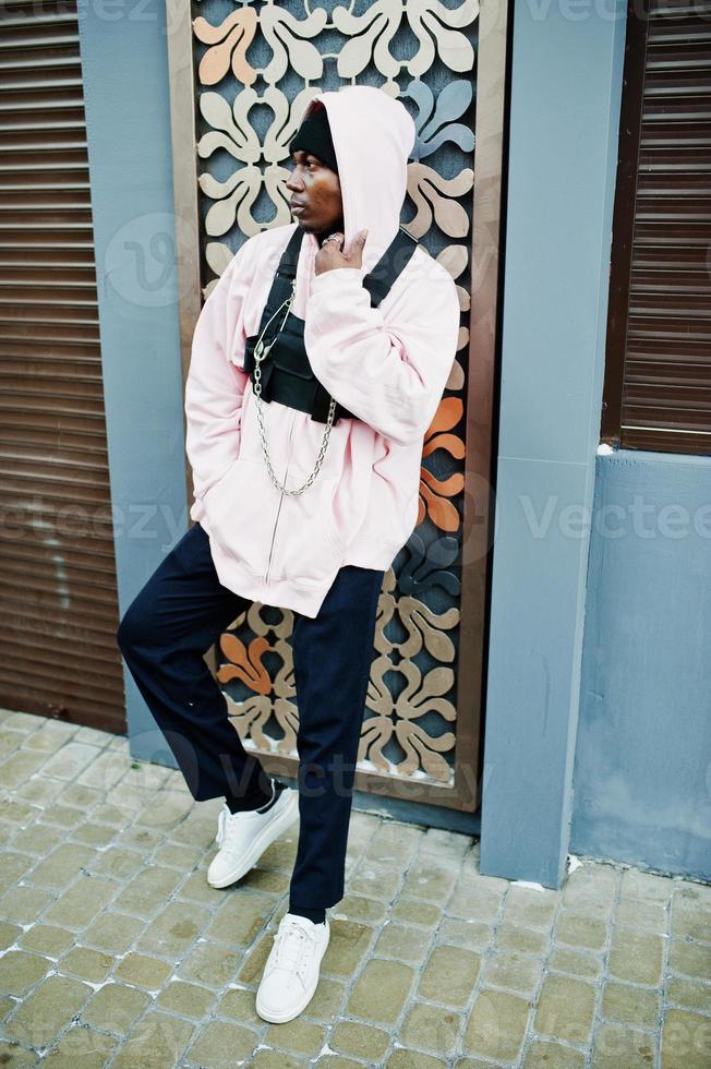 Elegante hombre afroamericano de estilo urbano con capucha rosa posó. rapero afro. foto