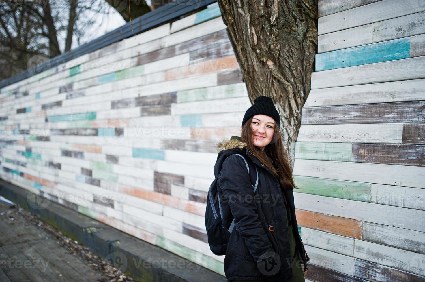 una joven usa sombreros negros contra una pared de madera. foto