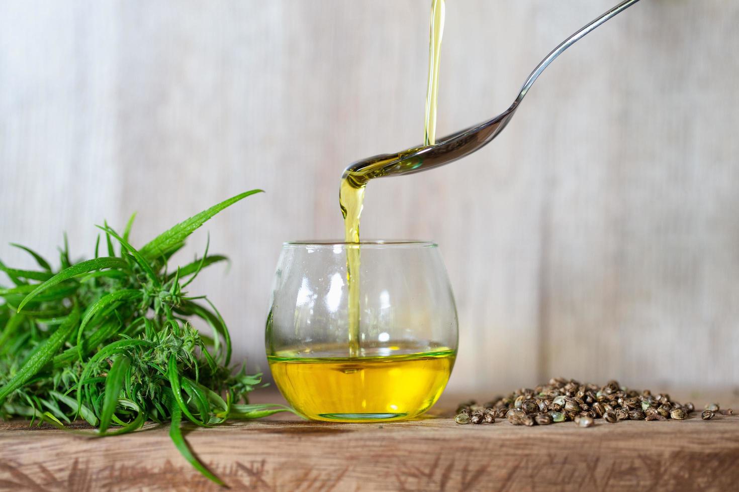 Pouring hemp oil into spoon, cannabis oil in a glass jar, Organic hemp oil, Concept of herbal alternative medicine. photo