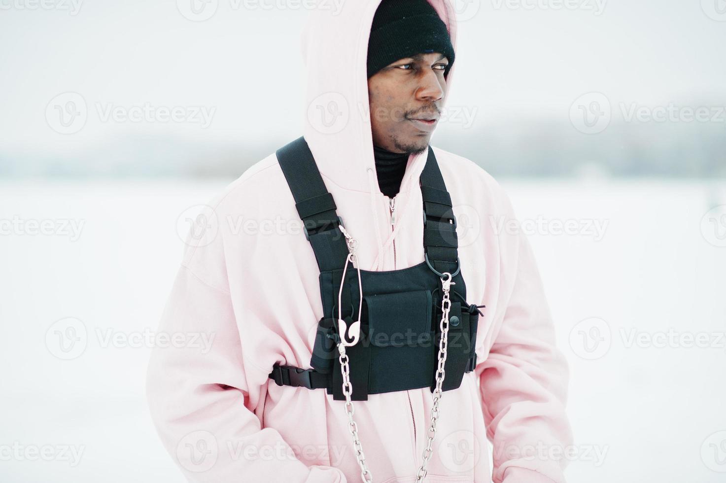 Stylish urban style african american man in pink hoodie posed at frozen lake in winter. photo