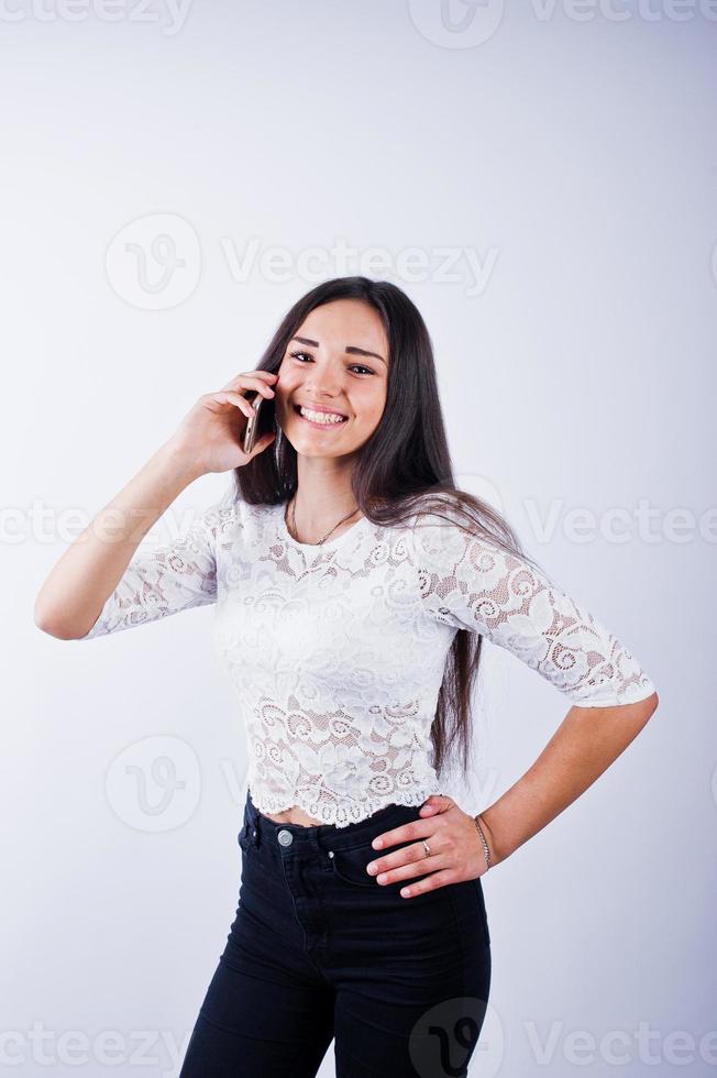 retrato de una mujer joven y hermosa con top blanco y pantalón negro usando su teléfono. foto