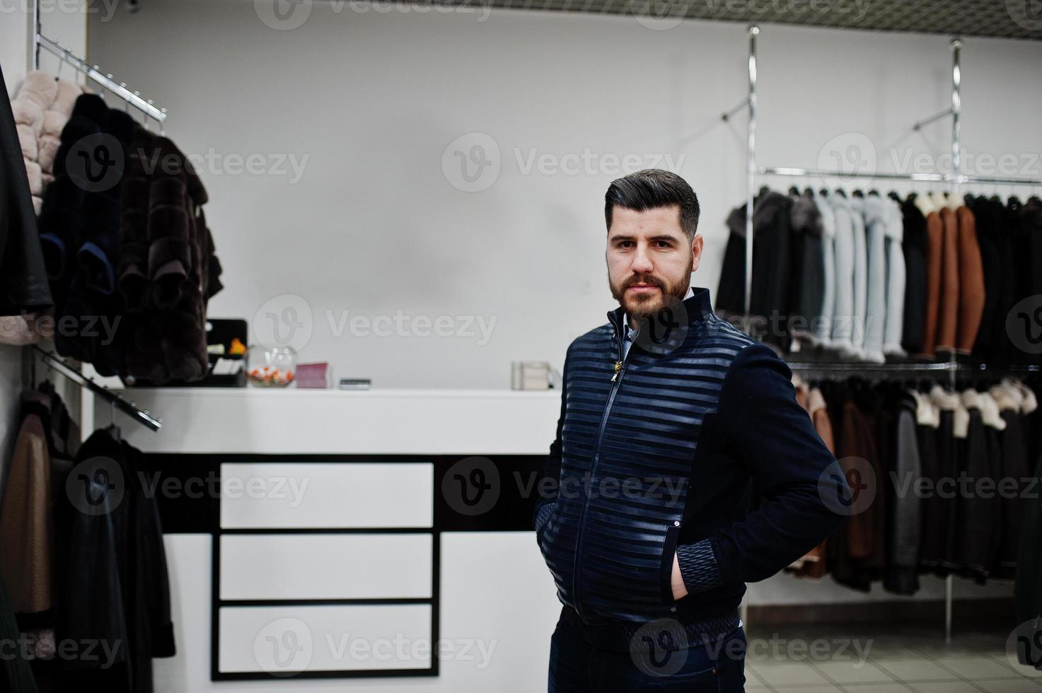 Stylish turkish man at the store of fur coats and leather jackets. Successful arabian beard man. photo