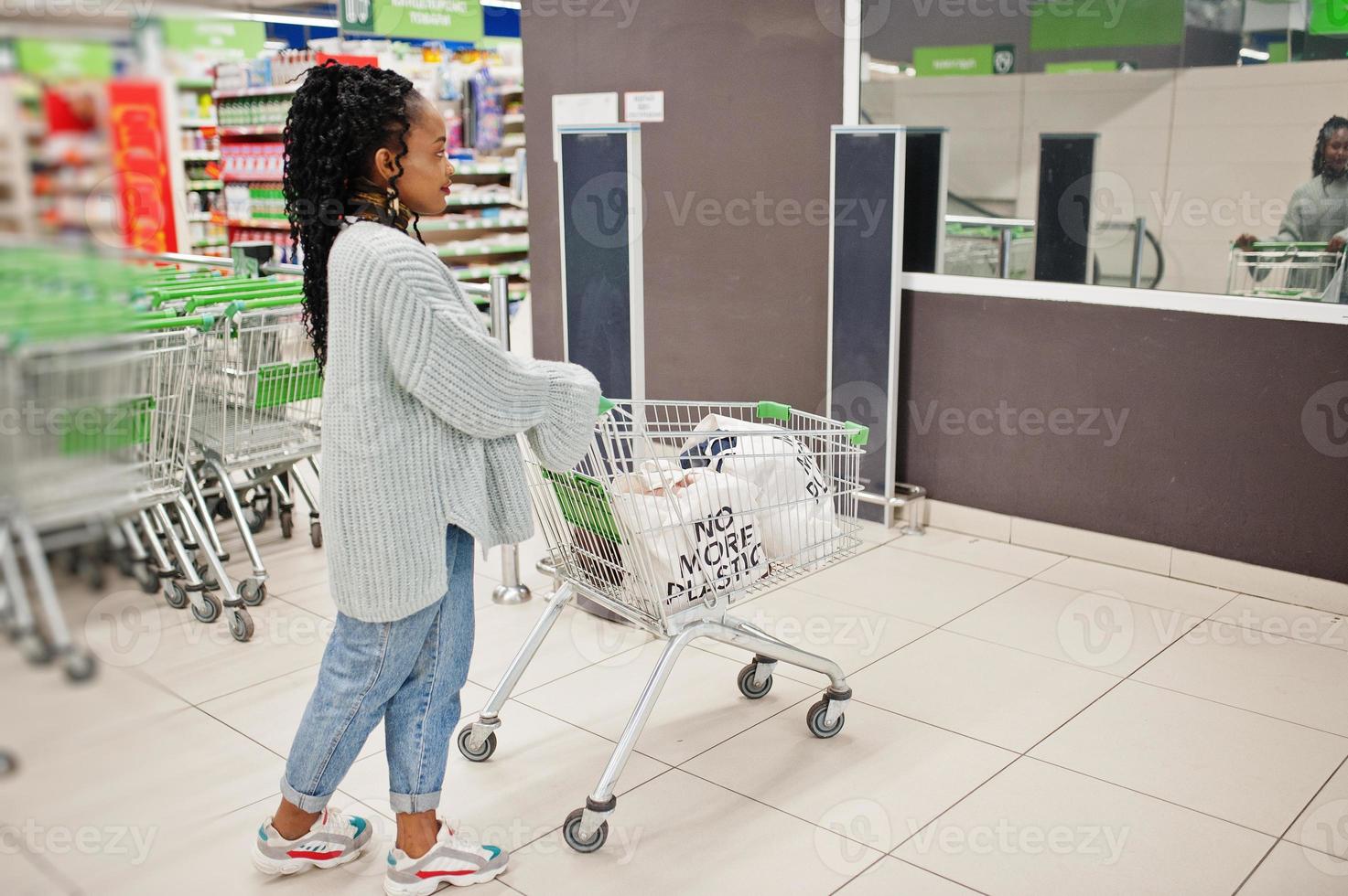 mujer africana con carrito de compras plantea mercado interior. foto