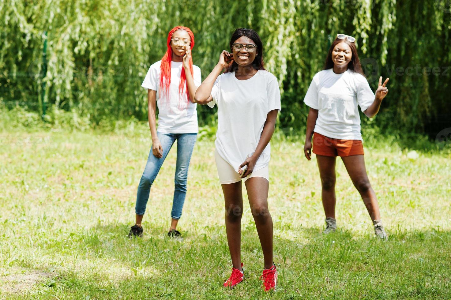 Three african american womans in park at white t-shirts. photo
