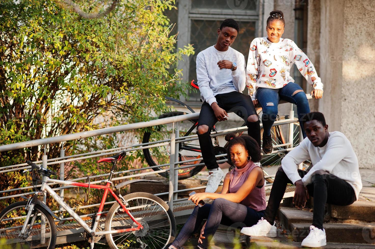 cuatro amigos africanos caminando por las calles de una ciudad antigua con bilkes. foto