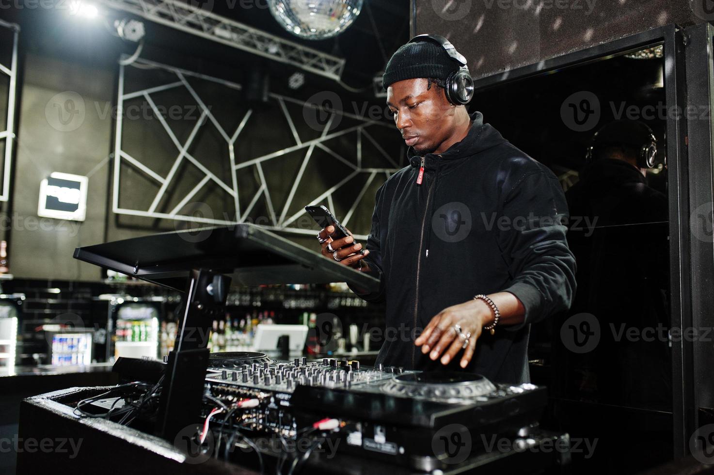 dj afroamericano toca música en cubiertas en el club nocturno. foto