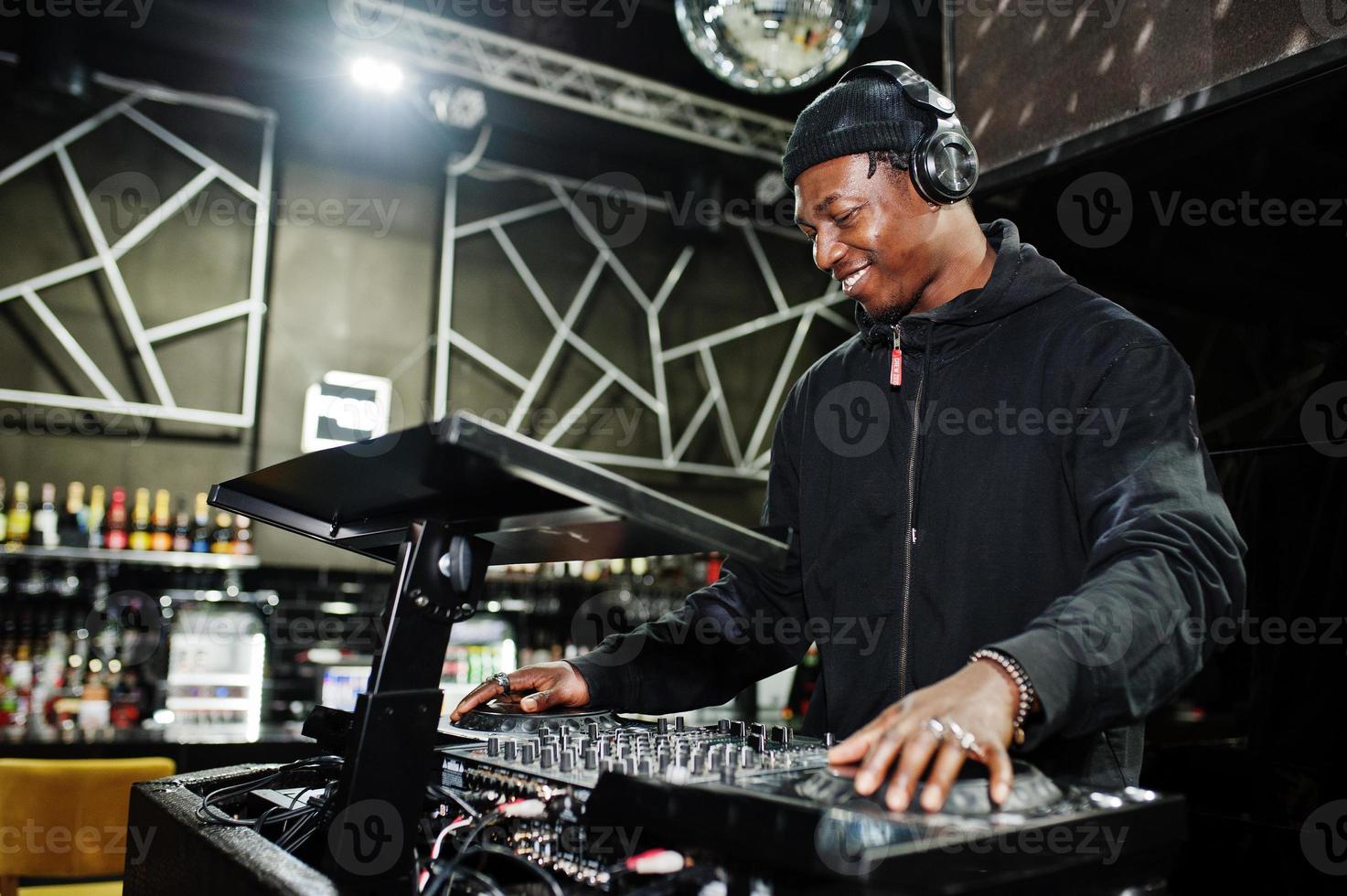 African american dj play music on decks at night club. photo