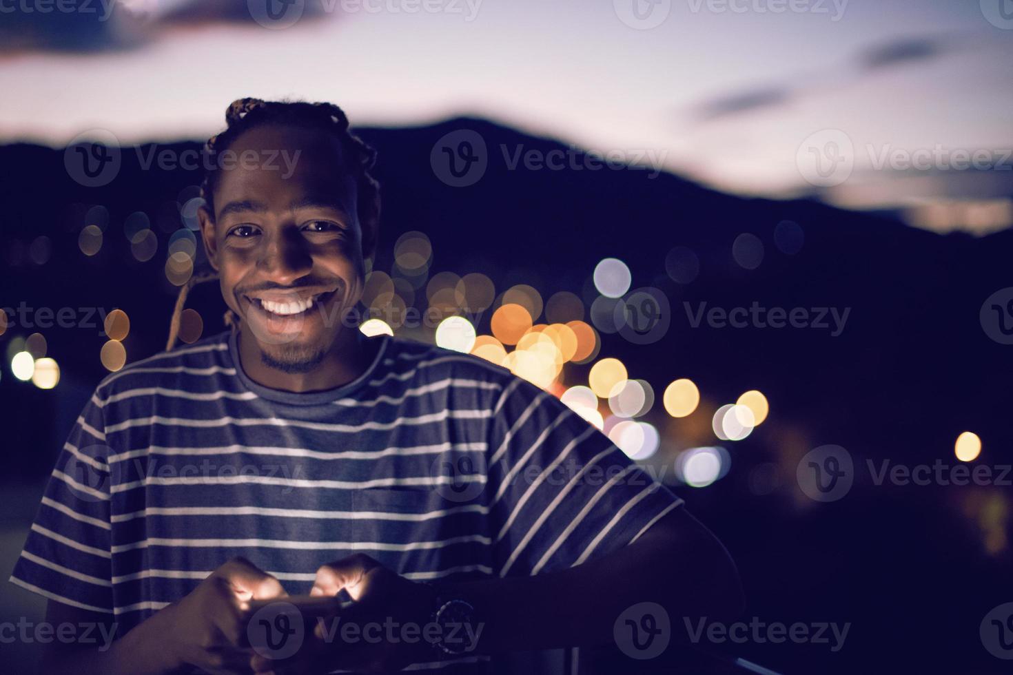 Young  Afro man on  street at night using phone photo