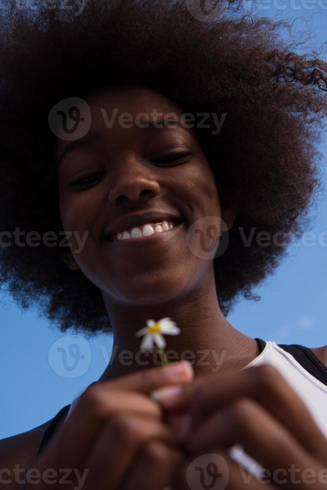 retrato de niña afroamericana con una flor en la mano foto
