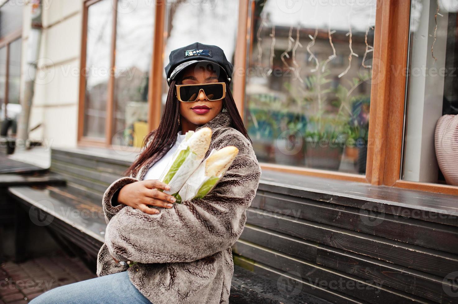 mujer afroamericana de moda con gorra gafas de sol y piel con dos rollos de baguette en las manos. 10430099 Foto stock en Vecteezy