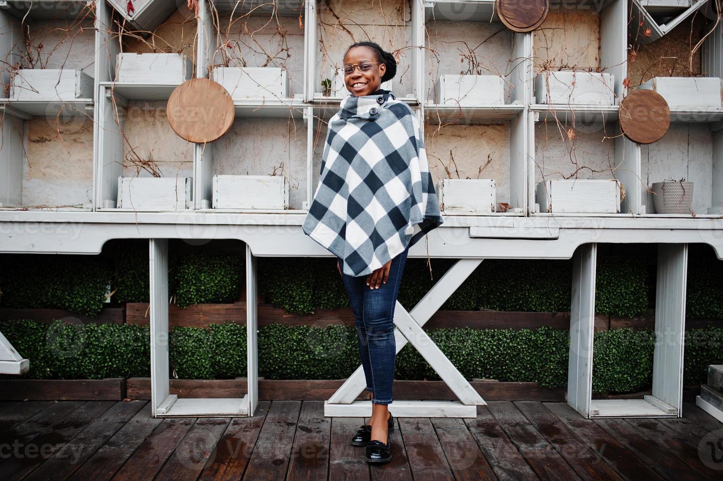 African woman in checkered cape and eyeglasses posed outdoor. photo