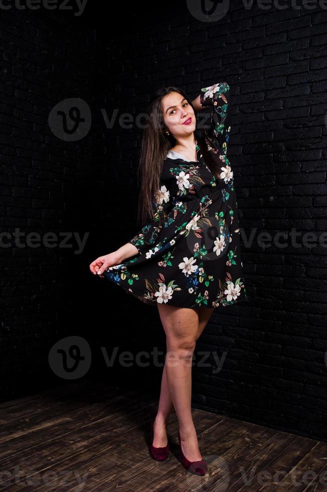 Portrait of a fabulous young woman in floral dress in the dark studio. photo