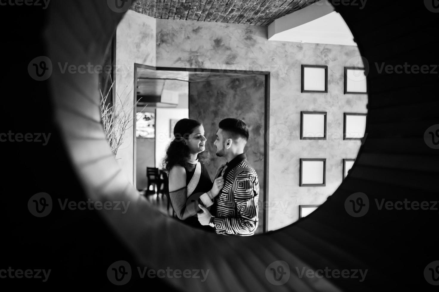 Lovely indian couple in love, wear at saree and elegant suit, posed on restaurant at round circle at wall. photo