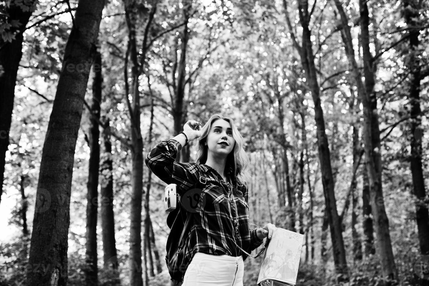 Portrait of a young beautiful blond woman in tartan shirt holding a map in the forest. photo