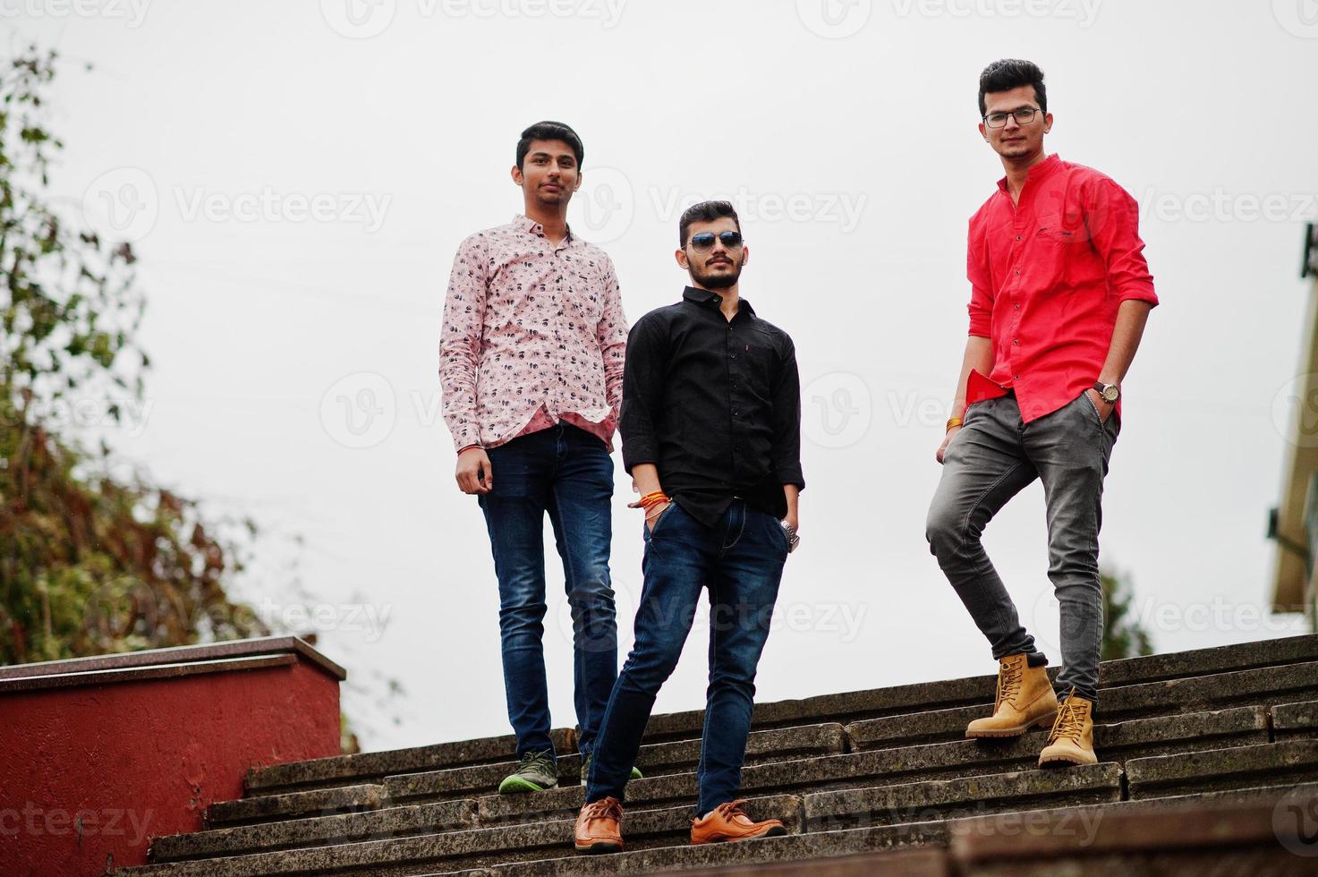 Three indian guys students friends walking on street. photo