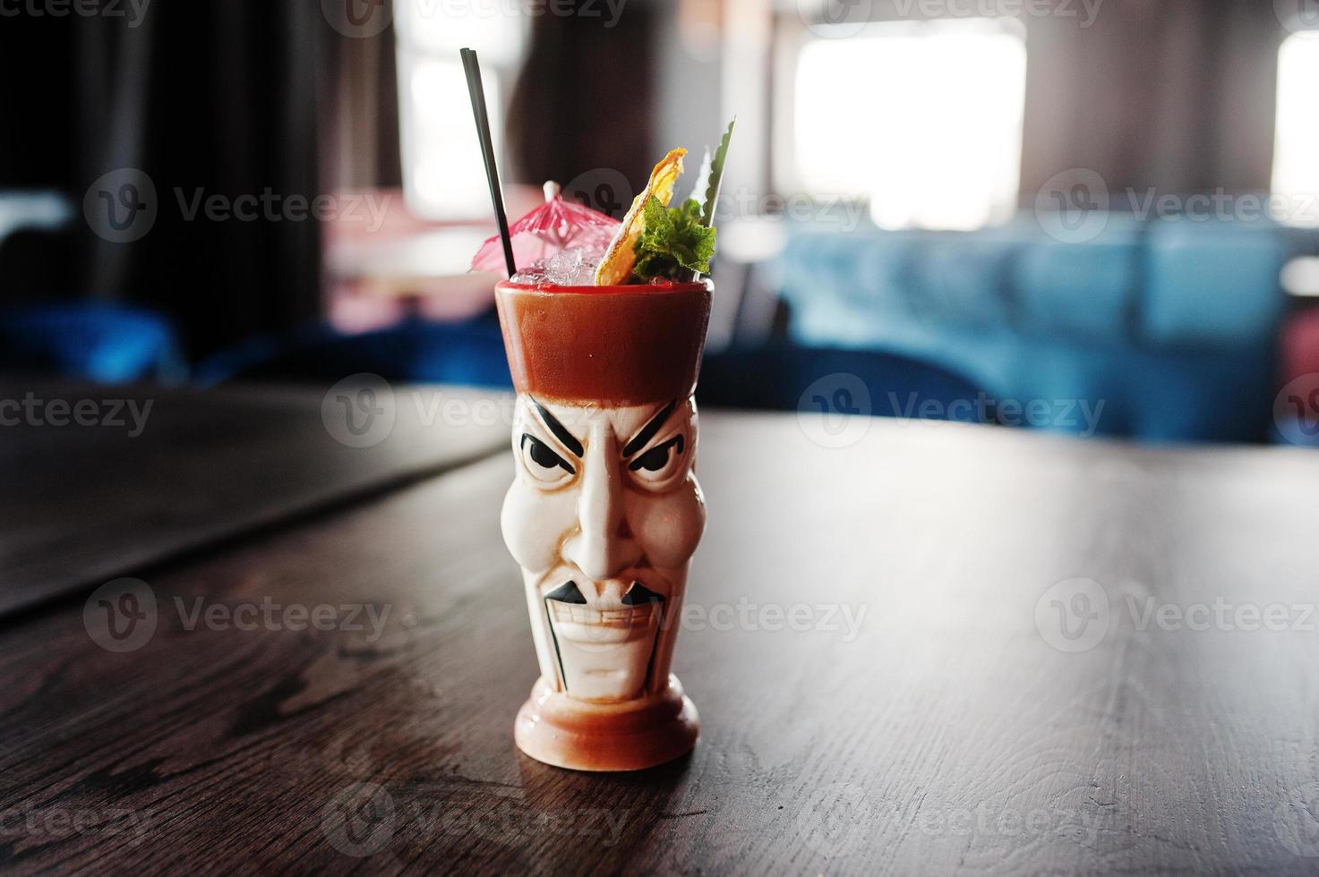 Alcoholic cocktail with mint and lime in originally voodoo earthen glass on bar table. photo