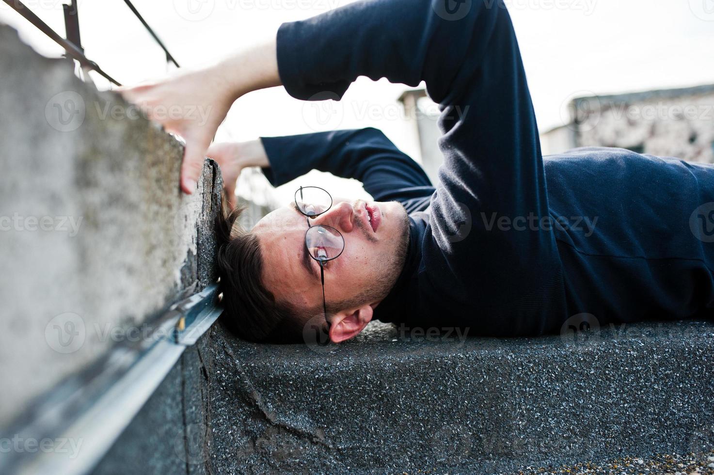 Dreamer stylish macho man in black golf and glasses posed on the roof. photo