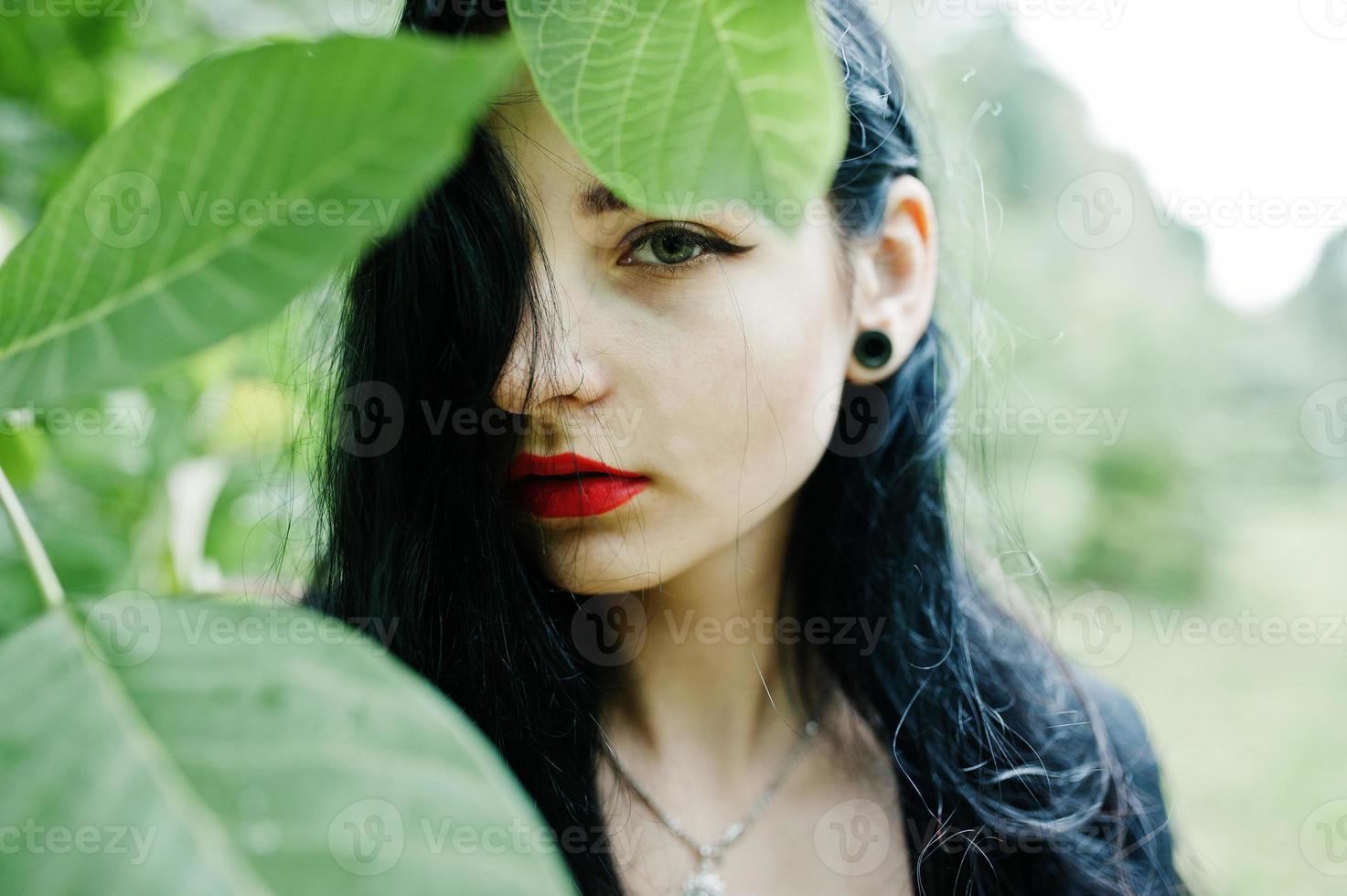 Sensual girl all in black, red lips and earlobe piersing. Goth dramatic woman. photo