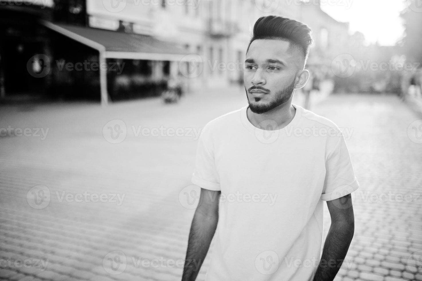 Stylish indian beard man at pink t-shirt. India model posed outdoor at streets of city sunset. photo