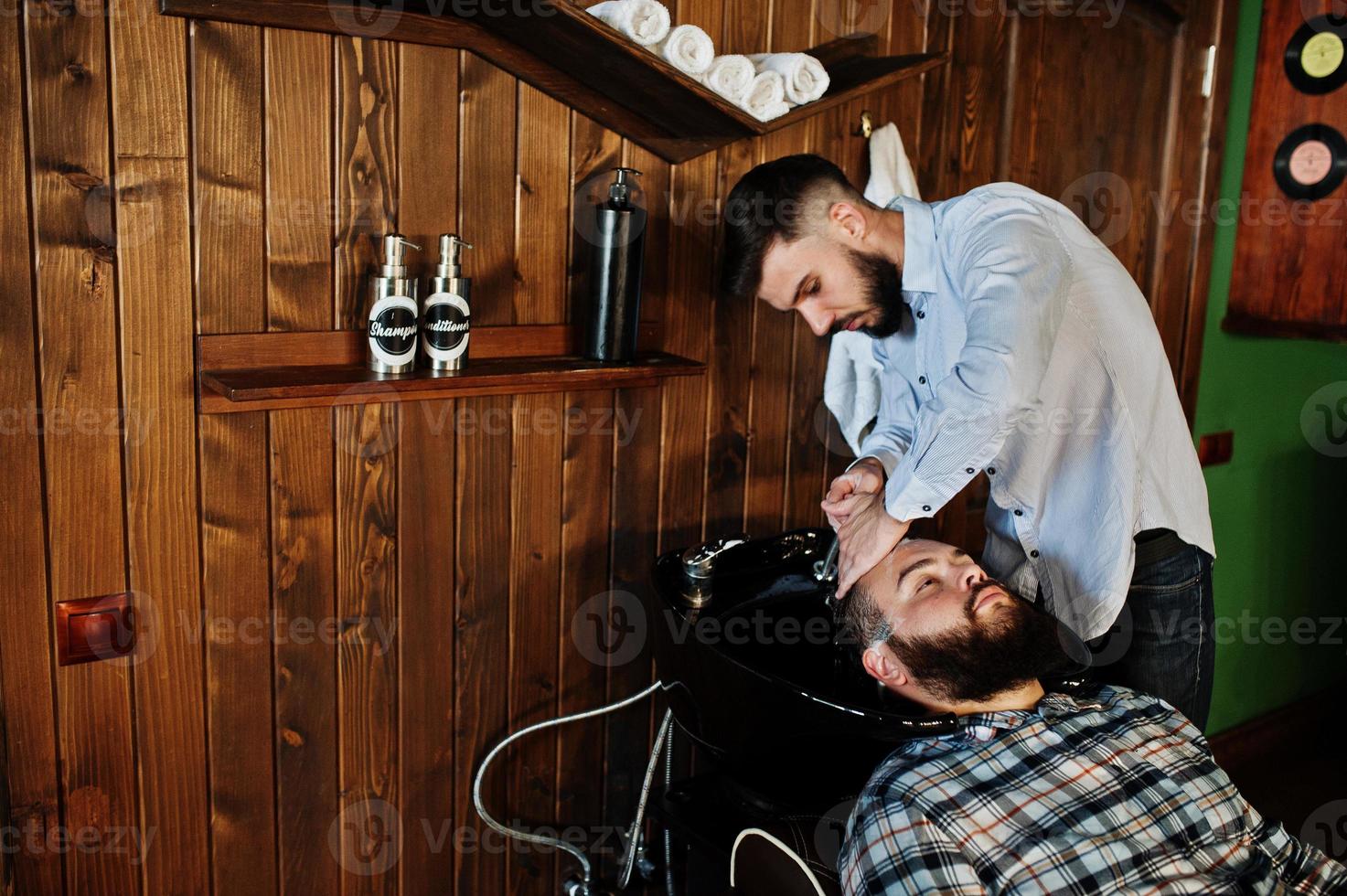 Handsome bearded man at the barbershop, barber at work. Washing head. photo