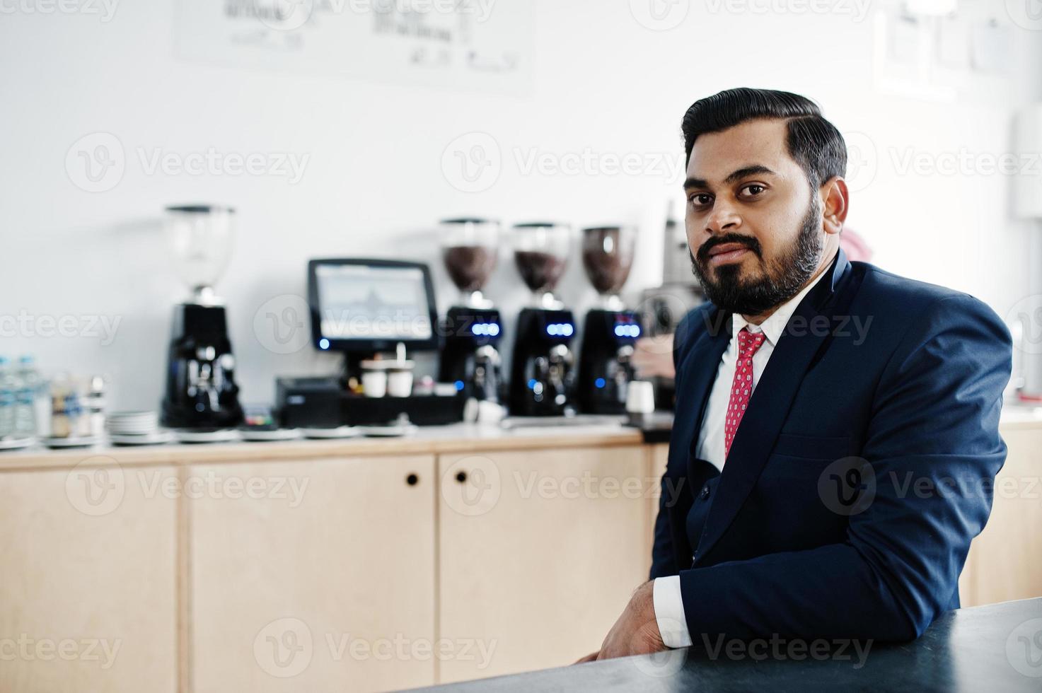 Stylish beard indian business man on suit sitting at cafe. photo