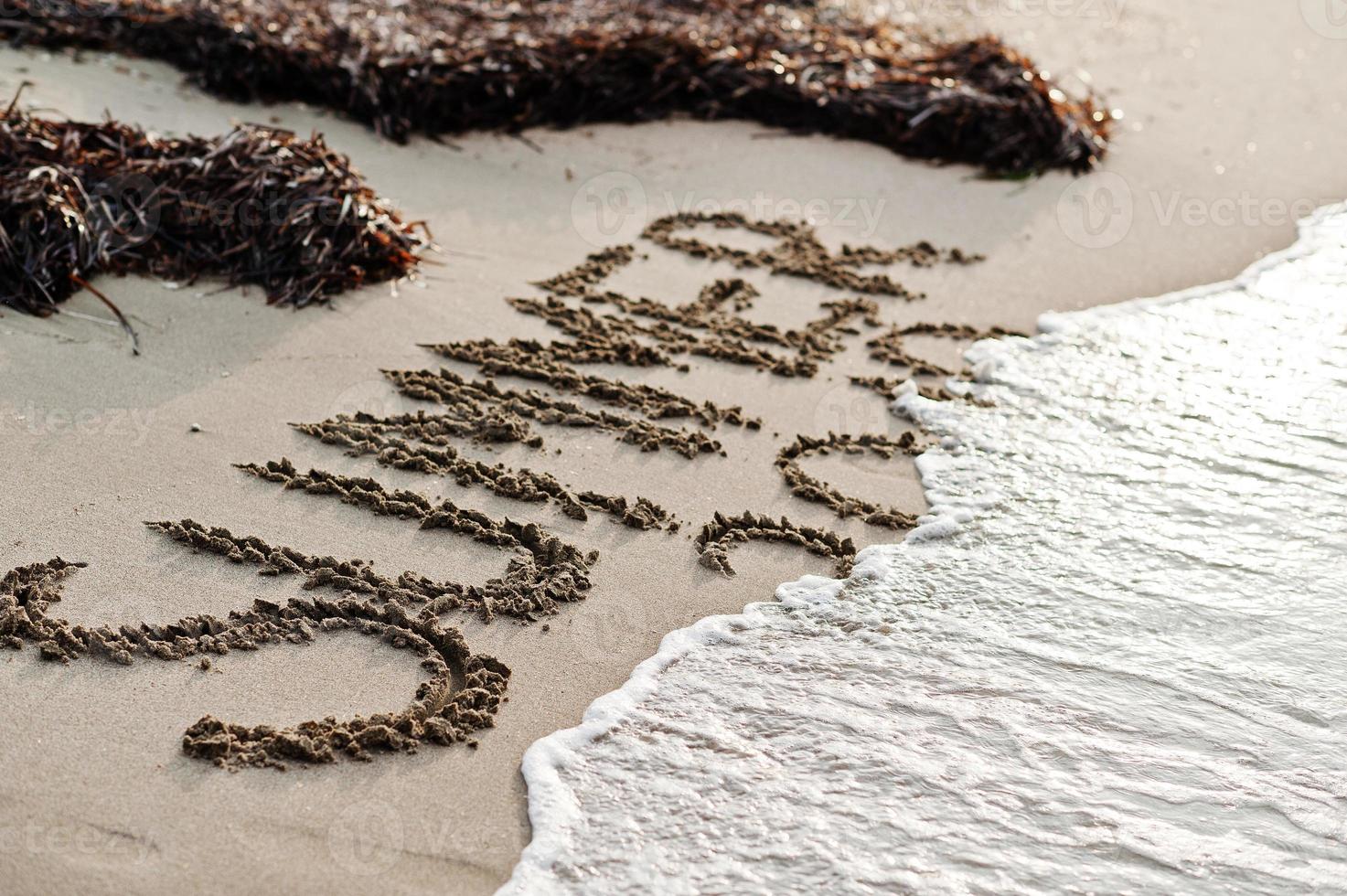 Inscription Summer covered by sea wawes and algae on the sand at beach. photo