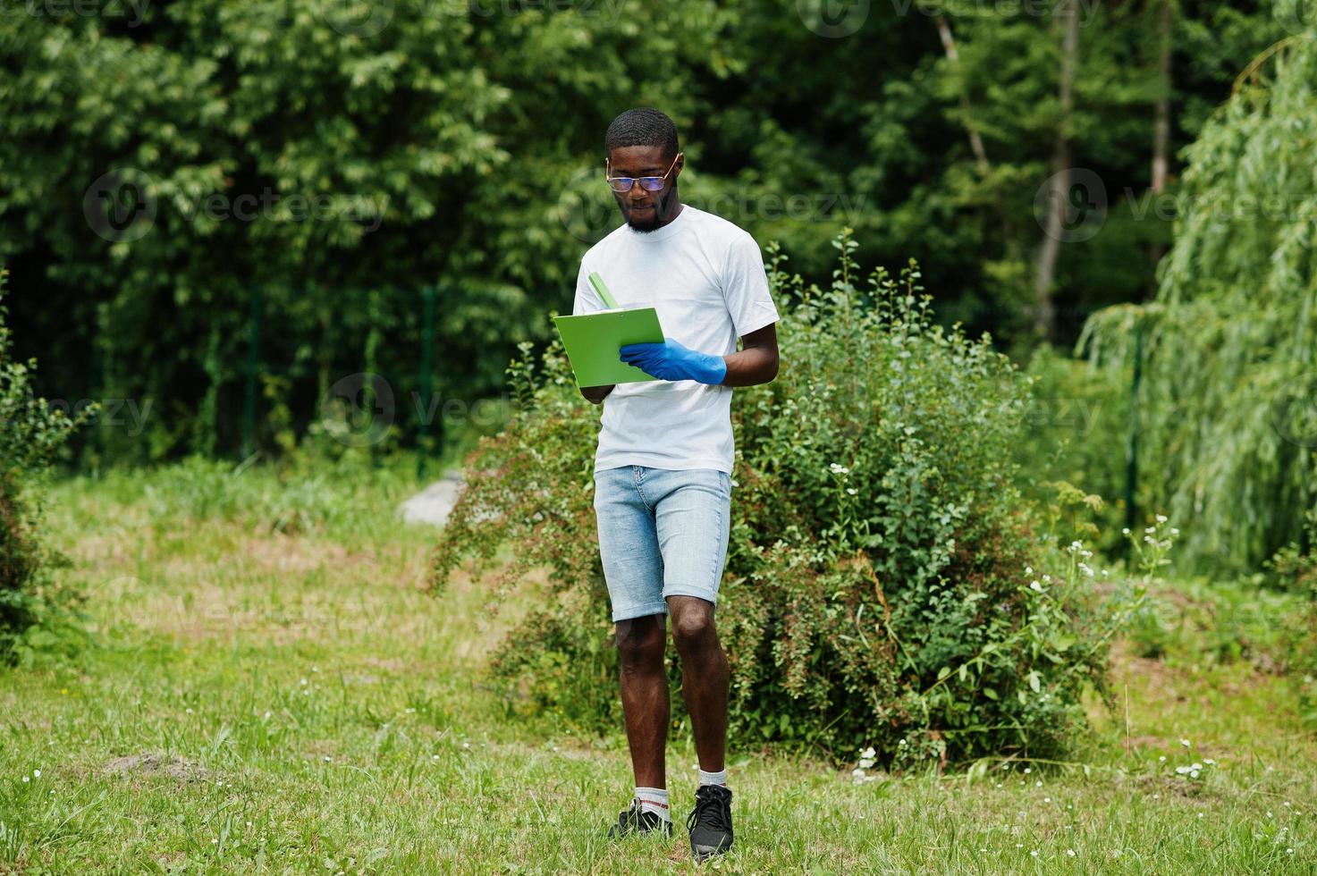 African volunteer man with clipboard in park. Africa volunteering, charity, people and ecology concept. photo