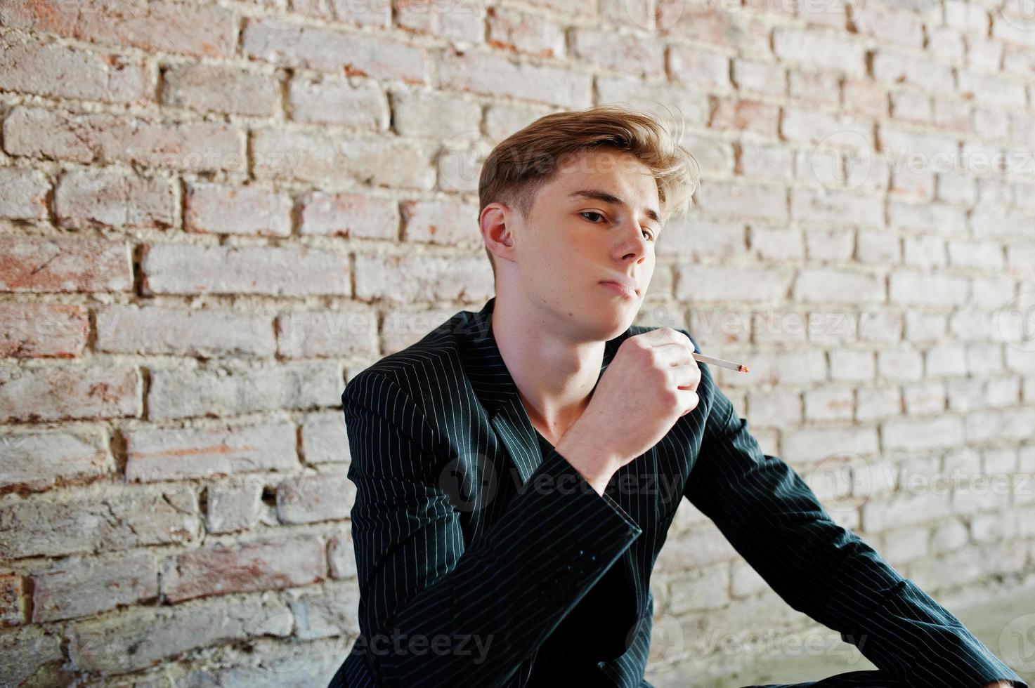 Young macho boy wear on blac stylish jacket smoking cigarette on streets. photo