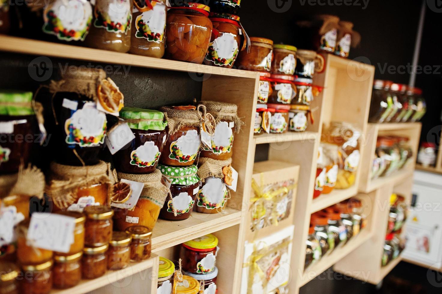 frascos de vidrio con diferentes tipos de mermelada y bayas de los estantes de un supermercado o tienda de comestibles. productos de conservas caseras. hecho con amor. foto