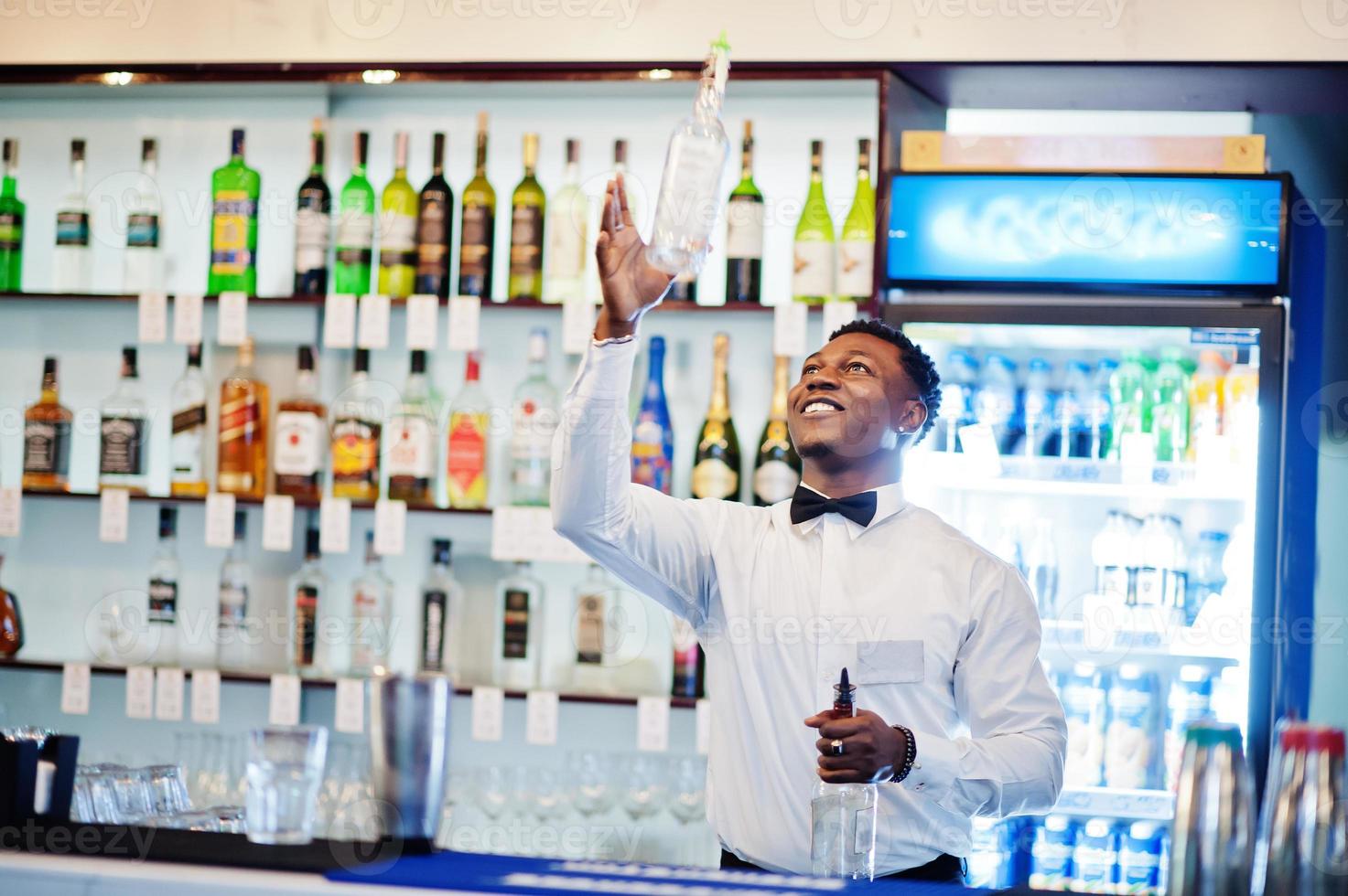bartender afroamericano en bar flair en acción, trabajando detrás del bar de cócteles. preparación de bebidas alcohólicas. foto