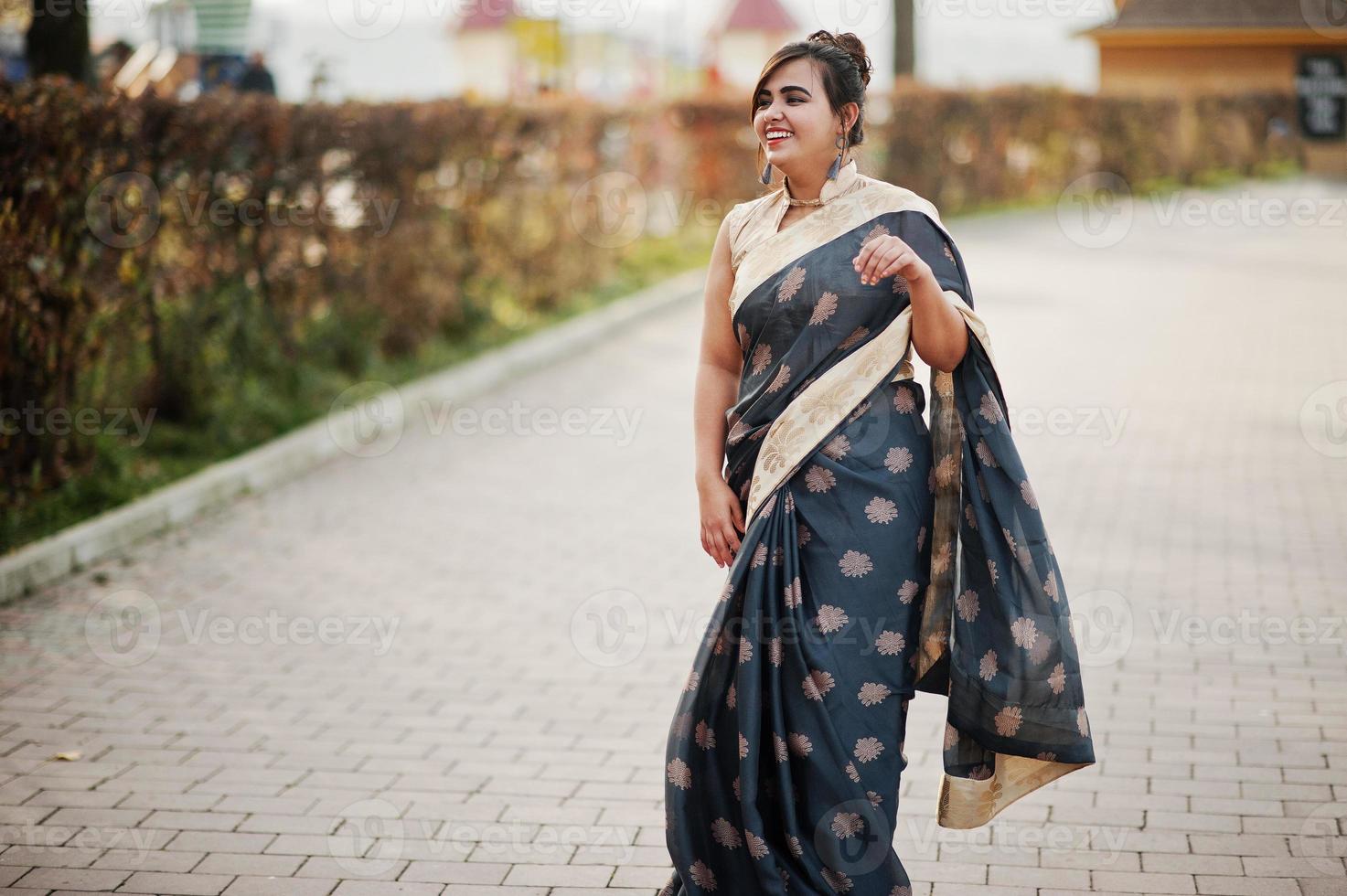 elegante morena chica india del sur de asia en sari bailando al aire libre. foto