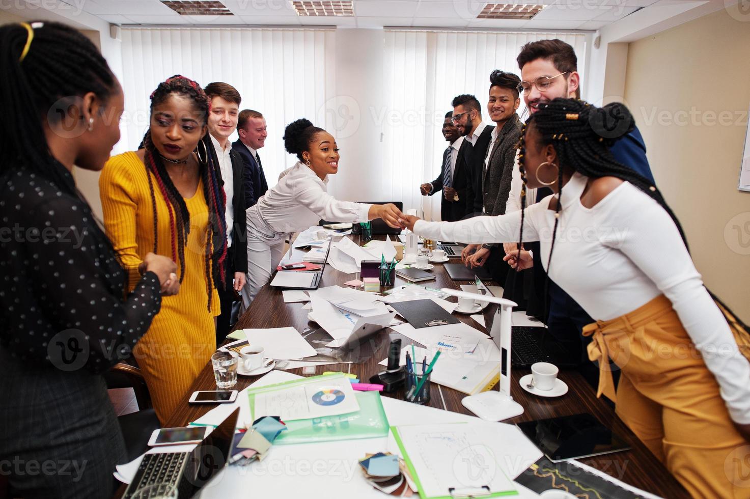 Good deal. Multiracial business team addressing meeting around boardroom table and shaking hands each other. photo