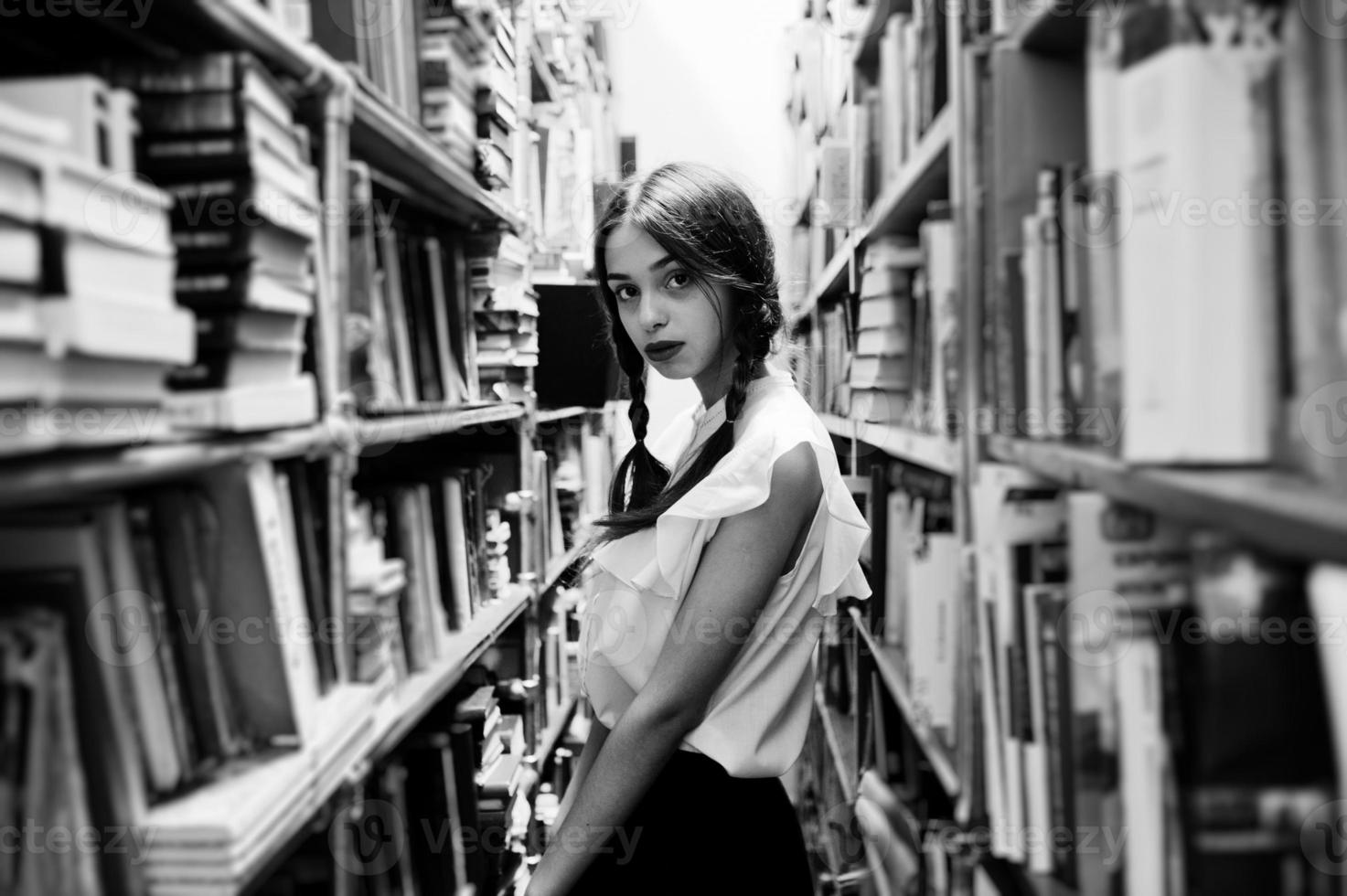 Girl with pigtails in white blouse at old library. photo