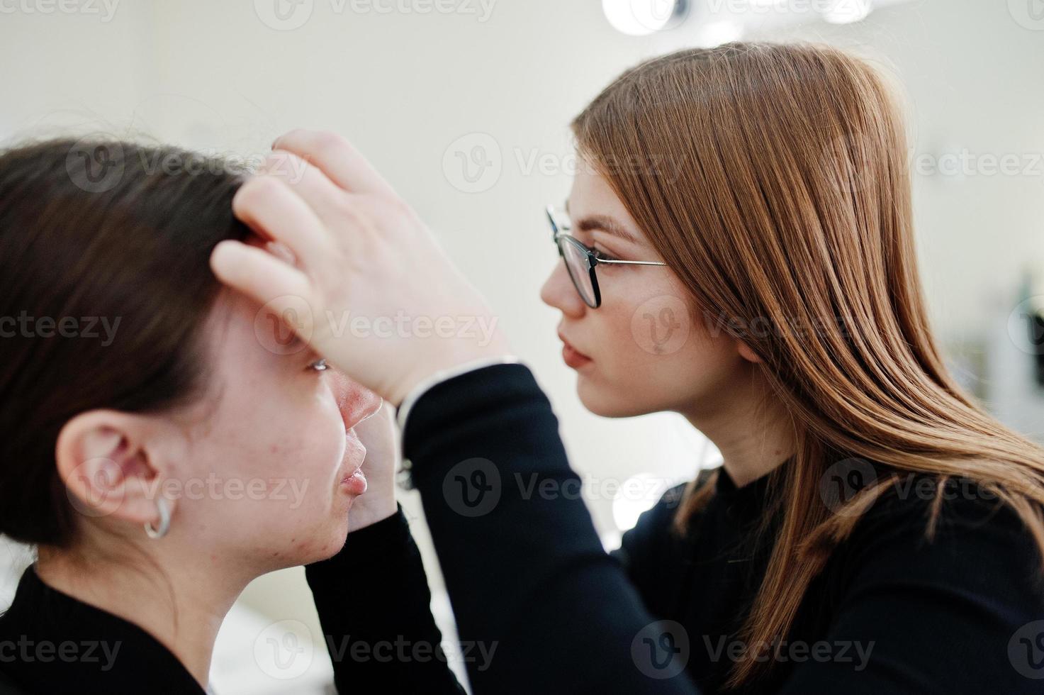 Make up artist work in her beauty visage studio salon. Woman applying by professional make up master. Beauty club concept. photo