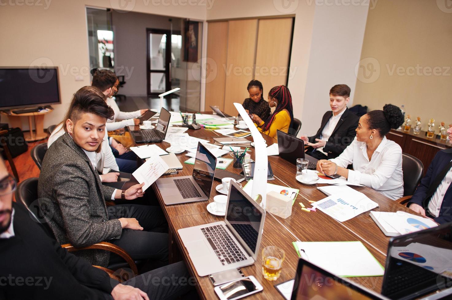 equipo de negocios multirracial que aborda la reunión alrededor de la mesa de juntas. foto