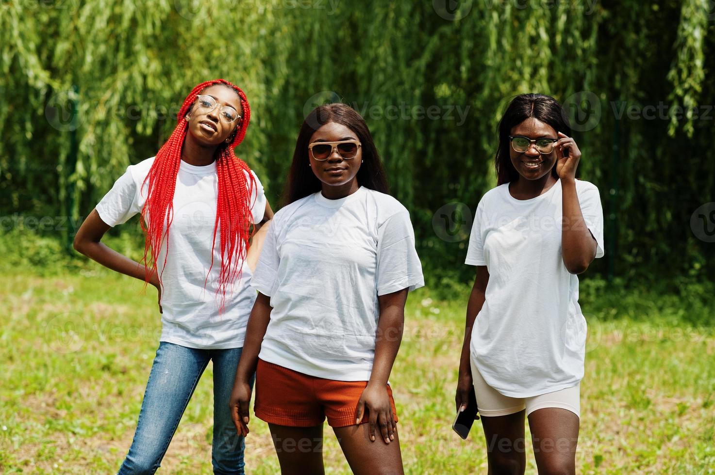 Three african american womans in park at white t-shirts. photo