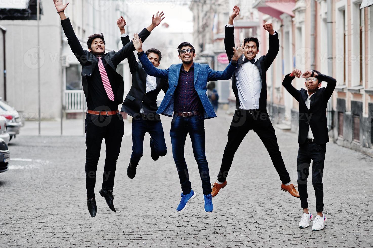 Group of 5 indian students in suits posed outdoor and jumping. photo