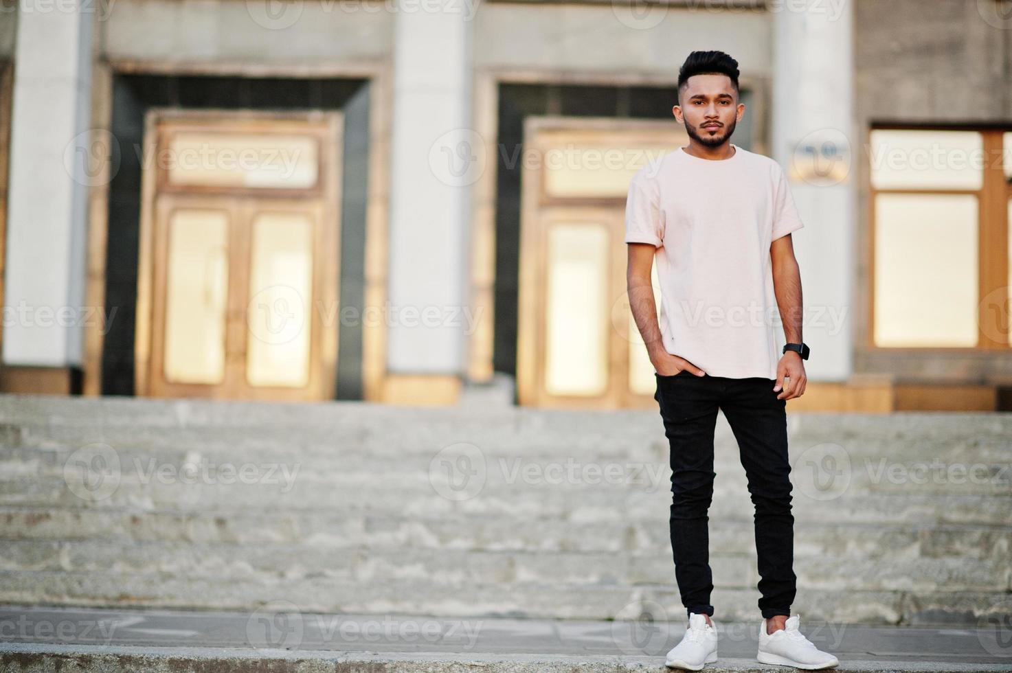Stylish indian beard man at pink t-shirt. India model posed at sunset of city. photo