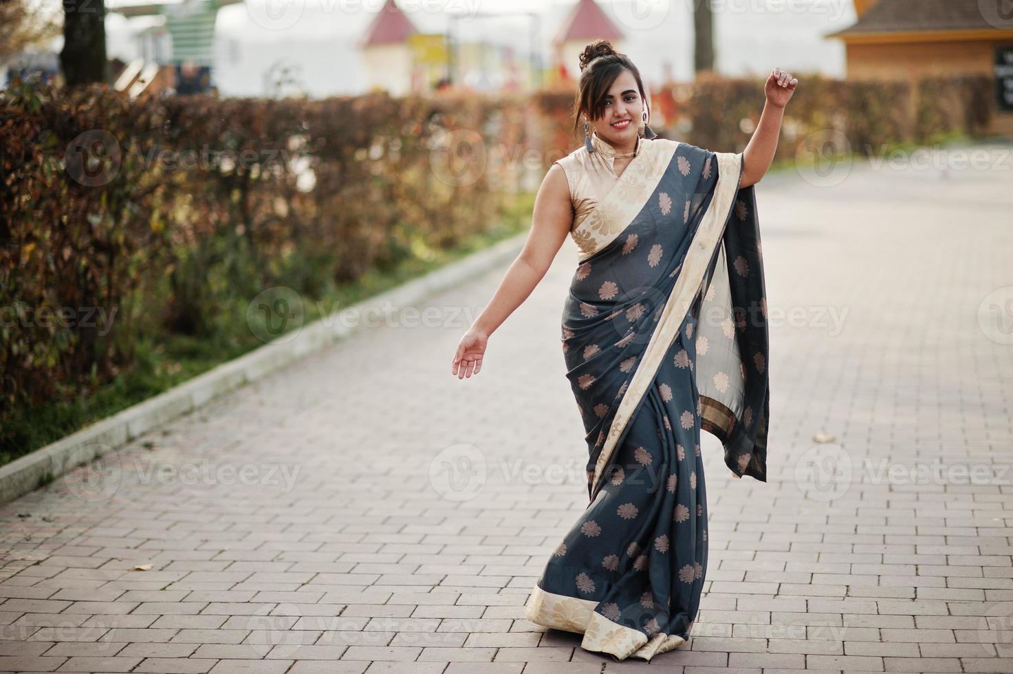 elegante morena chica india del sur de asia en sari bailando al aire libre. foto
