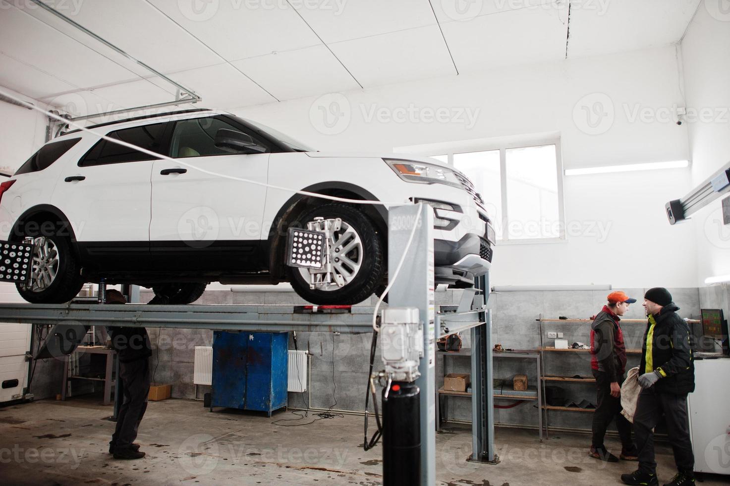 American SUV car on stand for wheels alignment camber check in workshop of service station. photo