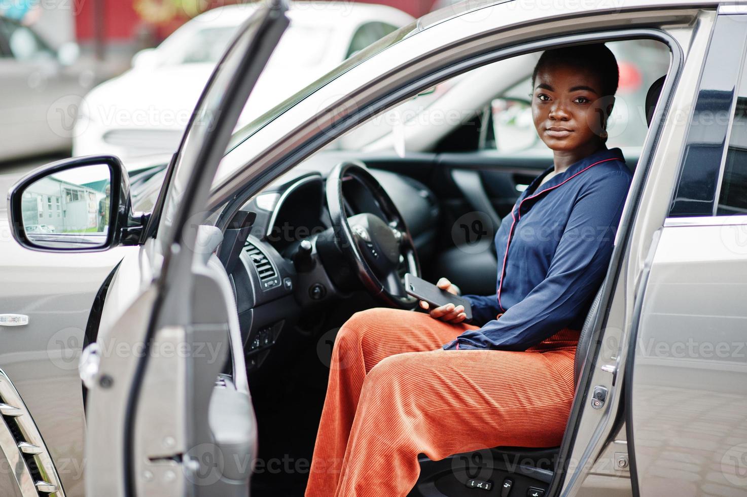 Rich business african woman sit on driver seat at silver suv car with opened door. photo