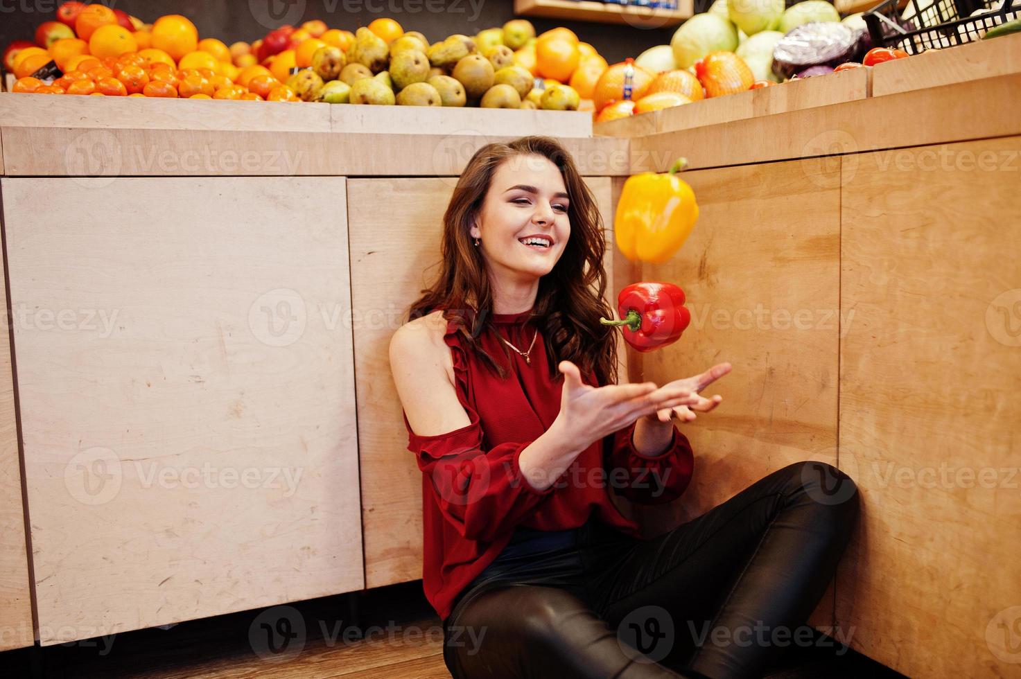 Girl in red throw peppers on fruits store. photo